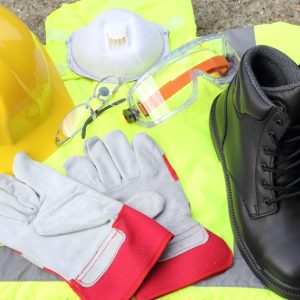 A close up of some personal protective equipment (PPE) stacked on each other, such as boots, hard hats, and goggles.