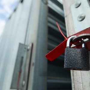 A close-up of a large storage container with the door open and a small padlock attached to a red handle.