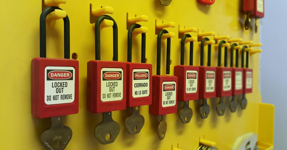 Several red Lock-Out Tag-Out locks hang from a wall. Each lock has a key protruding from the mechanism.