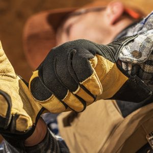 A professional construction contractor wears yellow leather impact gloves with black knuckle padding while at work.
