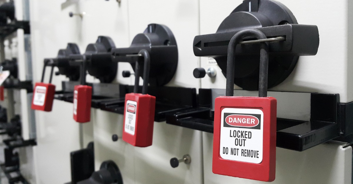 A metal combination padlock mounted on a stainless-steel roll-up door inside a warehouse or storage facility.